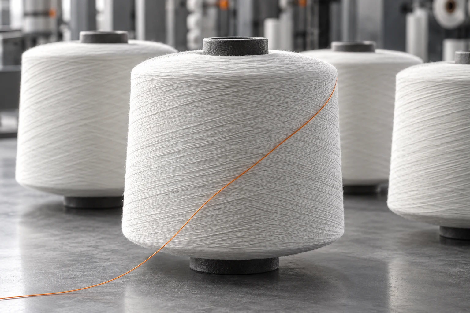White technical yarn cones with a single orange thread